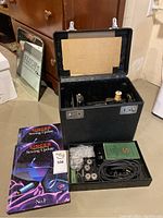 Black hard case open showing sewing machine and lower tray with accessories and books in foreground