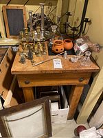 Candle holders of various sizes and styles including brass and ceramic, along with several picture frames, arranged on a wooden table.