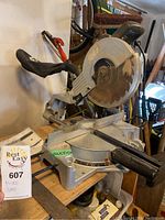 Overall view of the mitre saw showing the circular blade, metal base, and handle for operation.