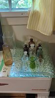 Full view of vintage glass collection showing textured glass tray, glass vases, and multiple glass bottles with stoppers.