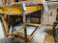 Side view of yellow tubular steel frame table on wheels