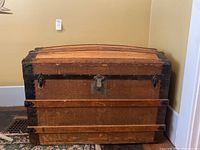 Front view of vintage wood chest showing arched top, metal hardware, and front locking latch