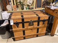 Front view of the wooden chest showing the metal hasps, lock plate, and metal corner reinforcements.