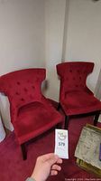 Two red velvet accent chairs placed side by side, visible overall condition and size.