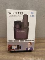 Front of the sealed box showing the Ansteker wireless microphone set with transmitter and receiver, highlighting 2.4G wireless frequency and uses like recording and online teaching.