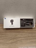 Open box showing Aobocam Q18 mini camera, adjustable mount, and USB cable