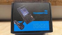 Box of FM Transmitter KM20 showing product image, FM Transmitter label, and car charger adapter with USB ports.