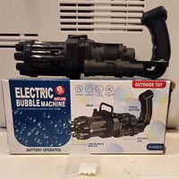 Electric bubble machine and its original box showing product details, bubble holes, battery jar, and activation button.