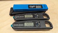Two Powlaken digital thermometers in black and blue, alongside a blue TDS & EC meter with black fabric pouch, all placed on a wooden surface.