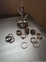 Photo of rings and chrome Umbra ring holder on metal surface, showing all 11 rings plus holder