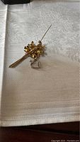 Gold filled floral bouquet pin with pearls and 10k white gold heart charm laid on fabric background