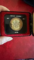 Commemorative silver coin with British Columbia coat of arms dated 1871 and 1971 in protective display case.
