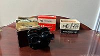 Photo showing black View-Master viewer, original box, and collection of View-Master reels and booklet on table.