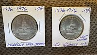 Two US Kennedy half dollar coins from 1976 Bicentennial, displayed in cardboard holders with handwritten labeling