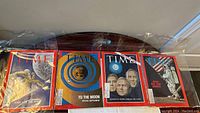 Four vintage Time magazines in plastic sleeves laid out to show front covers including moon and space themes.
