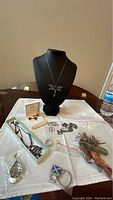 Wide view of the jewelry lot on a white cloth including dragonfly pendant, boxed amber jewelry, rings, bracelets, and charms