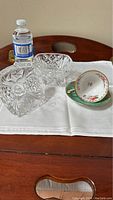 Photo showing the large cut glass candy bowl and lid with crisscross and star pattern next to Royal Albert floral cup and saucer