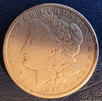Obverse side of 1921 Morgan silver dollar showing Lady Liberty's profile, date, and surrounding text.