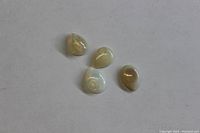 Four pear-shaped cabochon Ethiopian Welo fire opals shown on a neutral background illustrating their translucency and fire color.