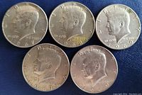 Front side of five Kennedy Half Dollar coins dated 1967 (two), 1968, and 1969 (two) showing JFK profile.