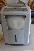 Front view of white GE dehumidifier showing air vents and water collection tank at bottom.