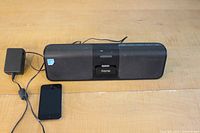 Black iHome speaker dock with power adapter and black iPod on table