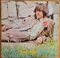 Front cover of James Taylor's first album on Apple Records showing him reclining against a stone wall.