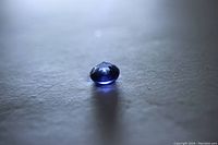 Close-up of round cut blue sapphire gemstone viewed at an angle showing its rich blue color and transparency.