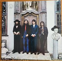 Front cover featuring The Beatles standing in front of a wooden panel door with statues.