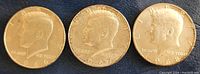Obverse view of three Kennedy half dollars dated 1966, 1967, and 1968 showing profile of John F. Kennedy.