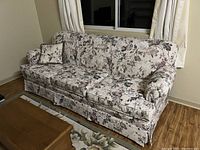 Angled view of the large 3-seat couch with floral fabric upholstery, showing the curved arms and cushions.