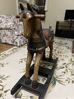 Front left quarter view of the hand-carved wooden rocking horse showing painted bridle and mane