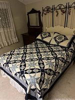 Photo of double bed with wire and fabric headboard, blue and cream star-patterned quilt, matching pillows, wooden side tables, and dresser with mirror in bedroom.