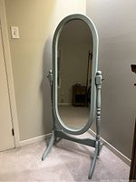 Freestanding light blue wooden dressing mirror with oval tilting mirror mounted within the frame, showing front view.