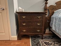 Front view of wooden dresser showing three drawers and brass handles, scratches visible on the surface.
