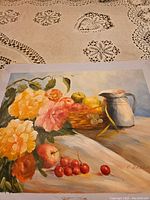 Photo of a 19x15.5 inch unframed canvas painting showing a floral arrangement with yellow and pink flowers, a fruit basket with apples and grapes, cherries on the table, and a white pitcher.