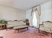 Photograph of the antique living room set showing the sofa, armchairs, end tables, and cocktail table arranged in the room.