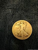 Obverse side of the coin showing a worn Walking Liberty design with date '1940', with noticeable wear and discoloration on a dark textured background.