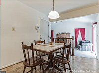 Dining area showing marble top square table with four dark wood spindle-back chairs on tile floor with pendant light above.