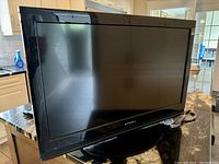 Front view of black 30 inch Dynex TV on stand showing screen and bezel.