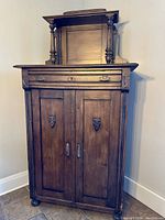 Front view of the antique solid wood corner hutch showing closed doors, drawer, and upper shelf with turned columns.