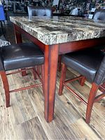 Close-up of table leg and chair leg showing wood finish and leather upholstery.