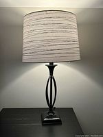 Front view of one lamp showing the light grey patterned shade and black metal base with oval open detail.