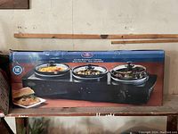Box showing three warming stations with black base and three 1.5 quart pots with glass lids