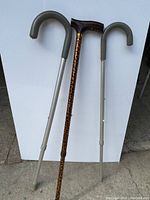 Photo showing three canes: two grey adjustable canes with curved handles and one leopard print cane with ergonomic handle, all in great condition.