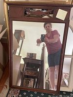 Full view of the rectangular wooden mahogany mirror with clear reflective surface, showing a person taking the photo and surrounding furniture.