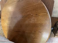 Top view of the round solid oak table top with visible wood grain and leaf insert in the center.