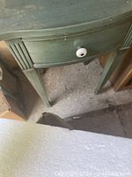 Image showing a small wooden turquoise side table with one drawer and round white knob, angled view highlighting legs and drawer shape with visible wear.