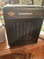 Front view of Kerosun Ceramica black ceramic space heater showing brand name and model on upper front, mesh metal grill covering heating elements.