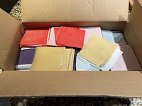 Open box with visible yellow, red, purple, white, and blue beeswax sheets stacked and spread out inside.